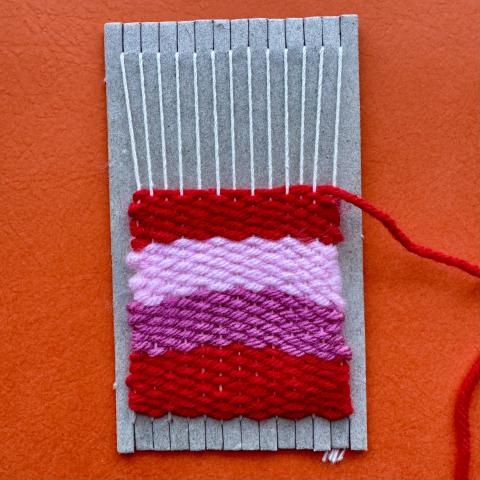 photograph of a small loom with 4 rows of weaving