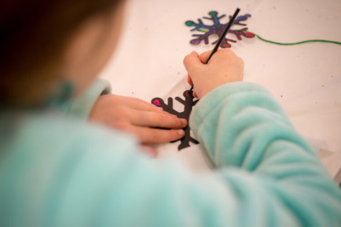 Child's hands decorating a snowflake craft