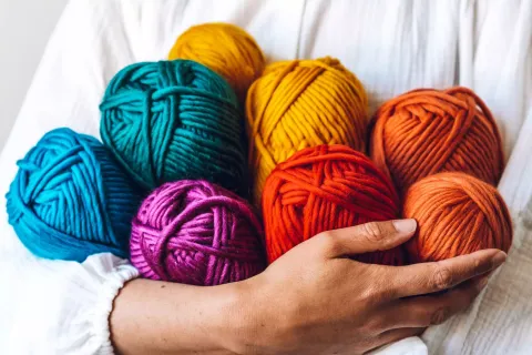 Close up of person holding several balls of yarn