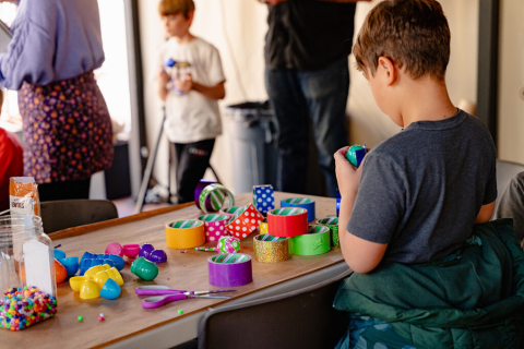 Image of a child creating a piece with multiple colors of duct tape. 