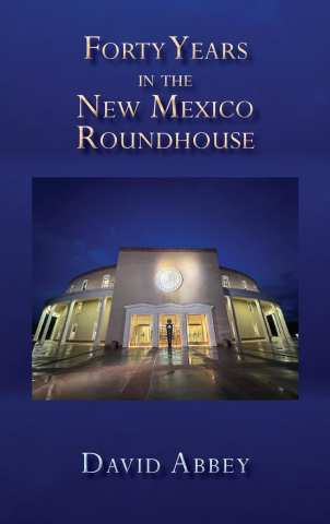 Navy blue book cover with photo of New Mexico Roundhouse building, title and author text that reads "Forty Years in the New Mexico Roundhouse, David Abbey"