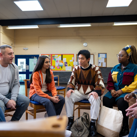 adults sitting in chairs in a circle talking