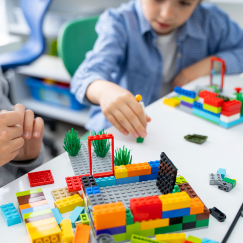 Children playing with colorful building blocks on a table.