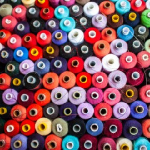 A close-up overhead view of many colorful spools of thread arranged in rows.
