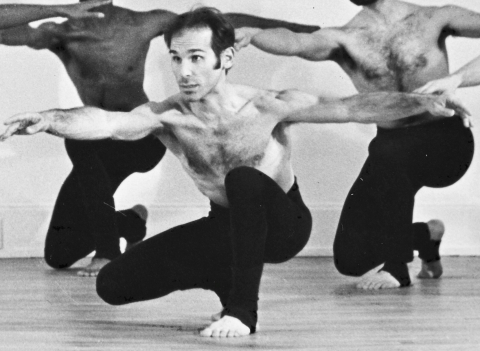 Choreographer Spider Kedelsky in a dance position with two dancers behind him.