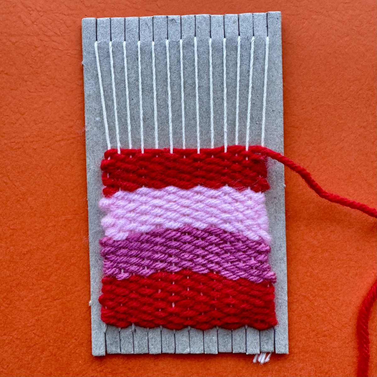 photograph of a small loom with 4 rows of weaving