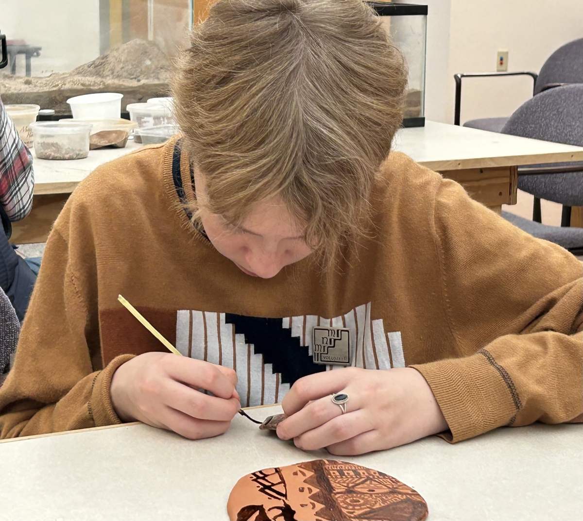 an older elementary student painting a pat sherd