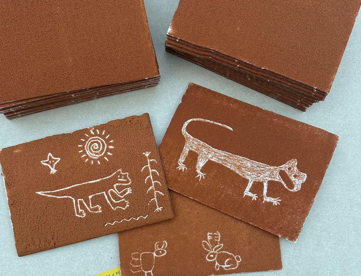 petroglyph image of lizards, bunnies, and other animals on brown surface