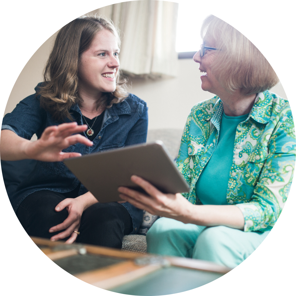 Young person helping mature person with tablet device
