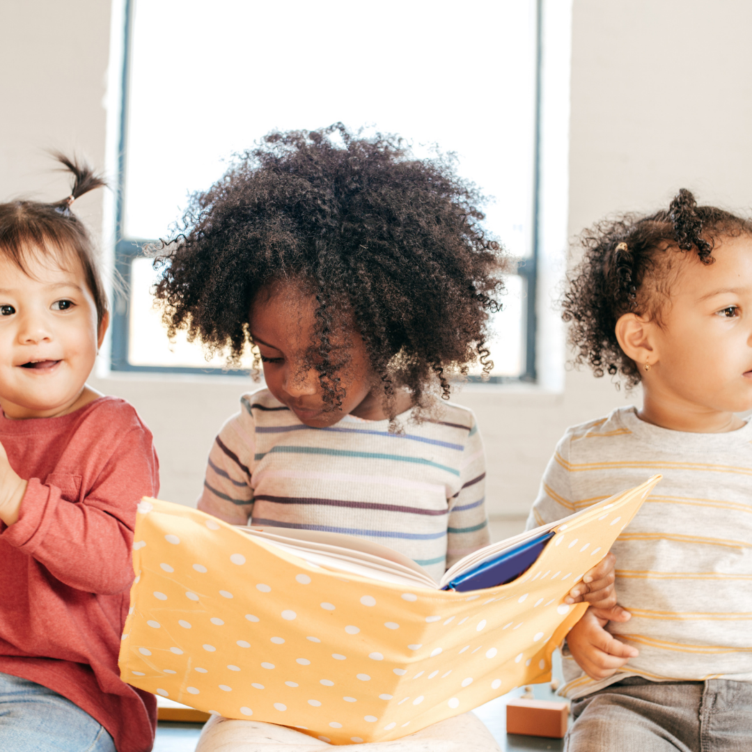 image of three toddlers one in the middle holding a book