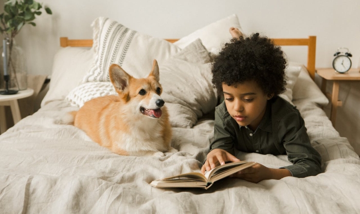 Small child reading to dog in bed